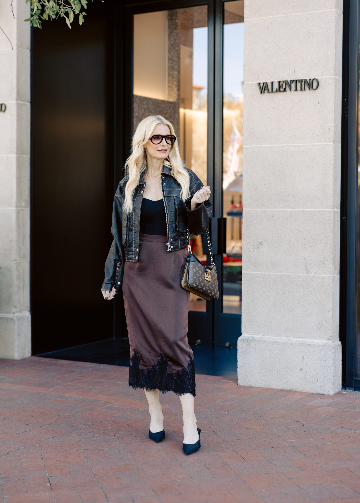 Fashion stylist for women over 40 wearing a bomber jacket with a silk midi skirt instead of a moto jacket which is out of style for winter 2025.