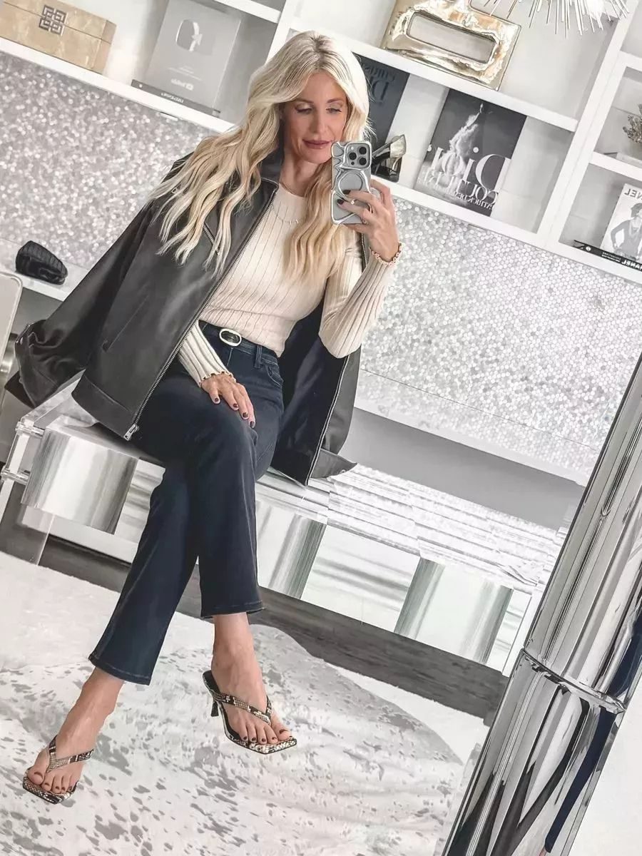 Dallas fashion stylist wearing faded black wash jeans with a cream sweater and leather jacket as one of the hottest 2026 denim trends