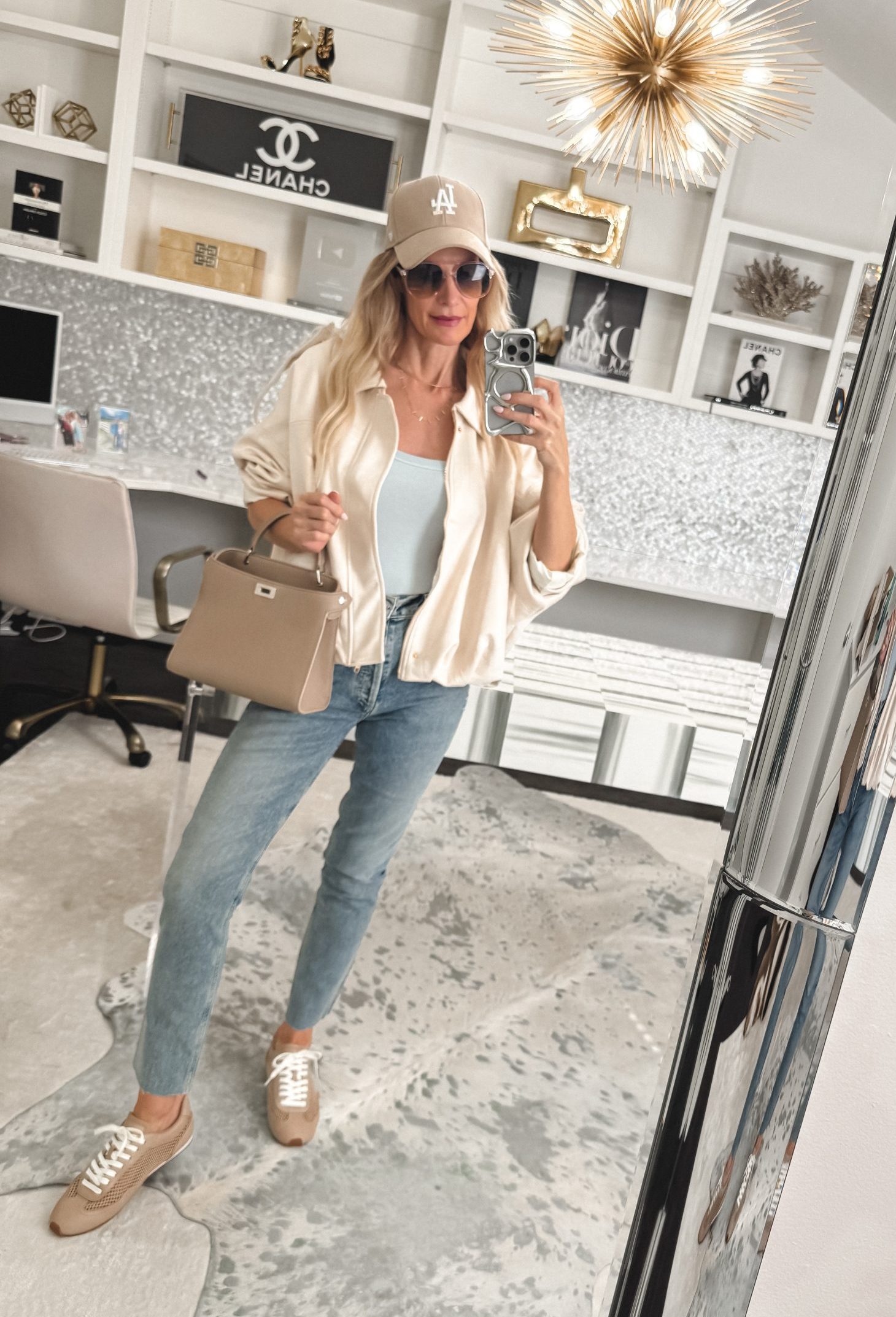 Over 40 fashion blogger wearing a hat, handbag, sunglasses and a necklace stack with her jeans and sneakers look to elevate the whole look and to avoid Sneakers and jeans outfit mistakes.