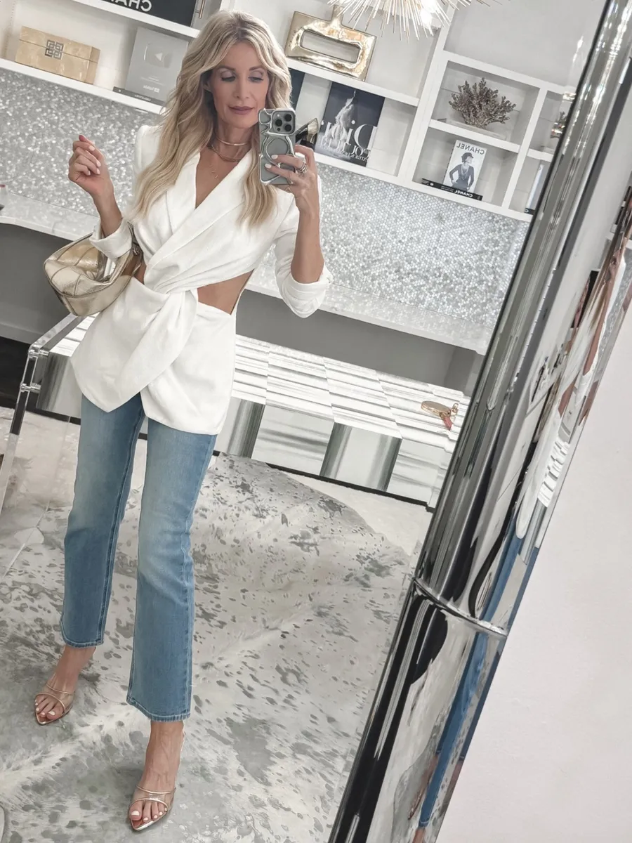 Dallas fashion influencer wearing a cut out blazer with clear low heels and straight leg jeans.