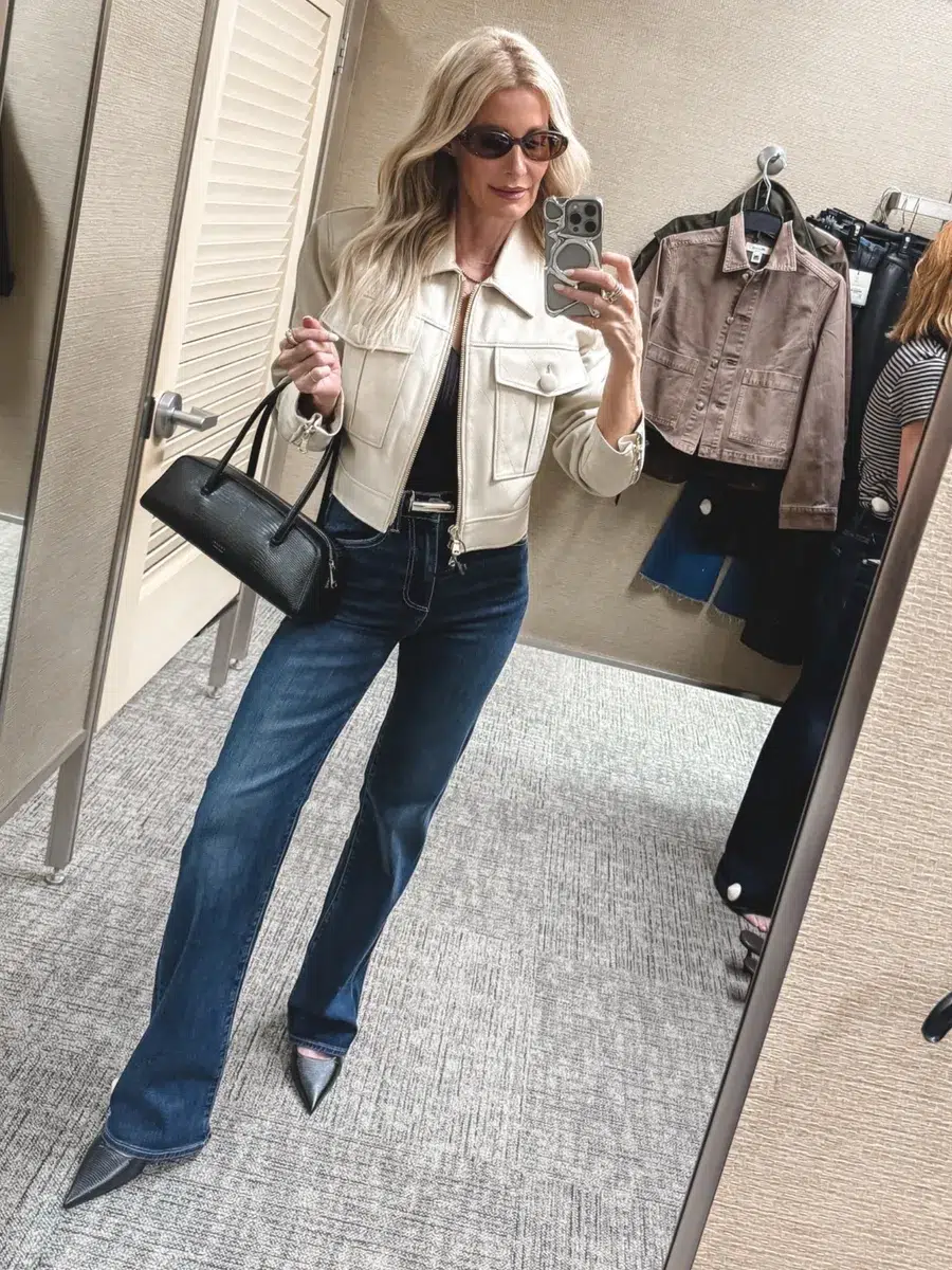 Fashion icon for women over 40 from Dallas wearing slim bootcut jeans with a ivory leather jacket and black heels.