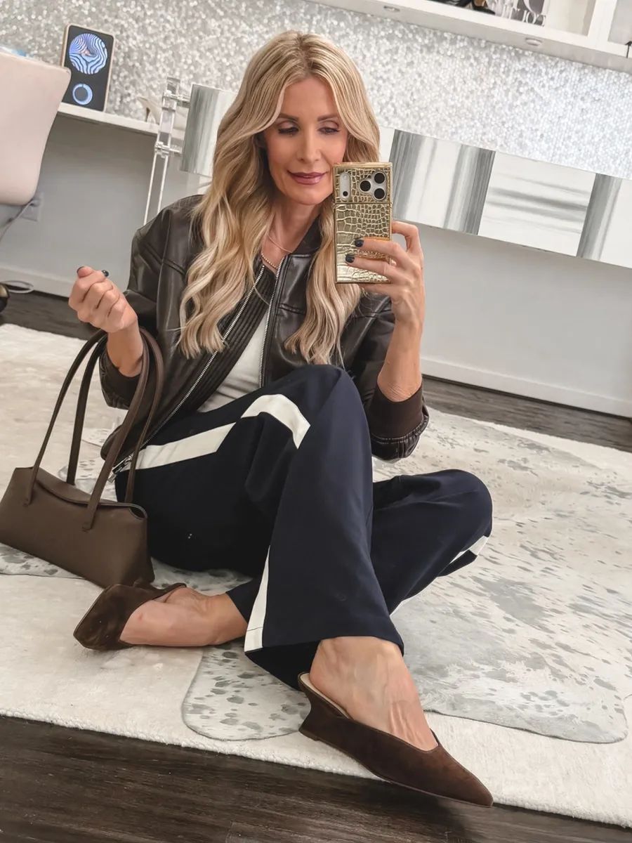 Fashion blogger for women over 40 wearing brown suede wedges with track pants and a leather jacket as one of the hottest 2026 fall shoe trends.