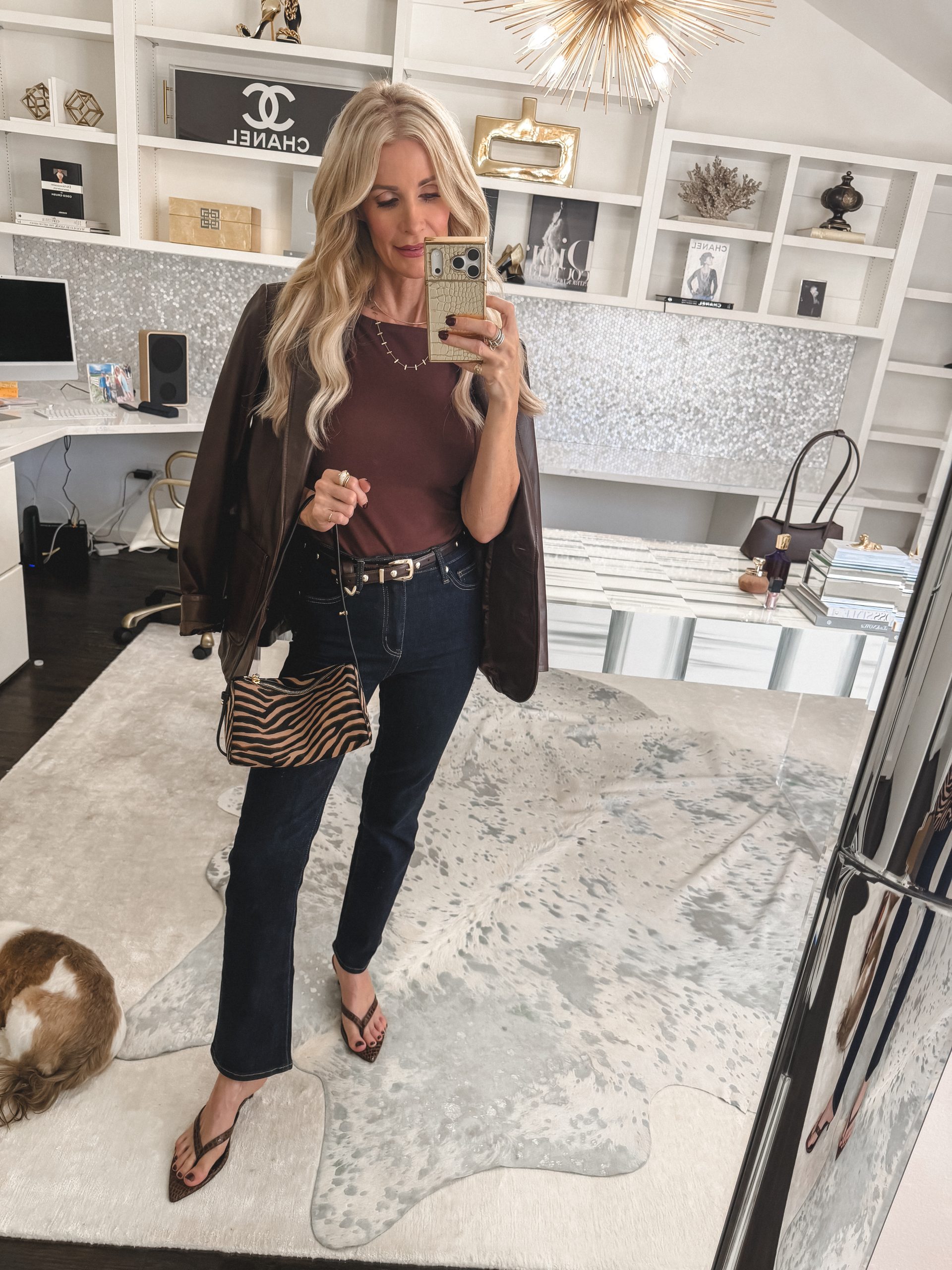 Fashion blogger for women over 50 wearing dark wash jeans with brown blazer and burgundy top.